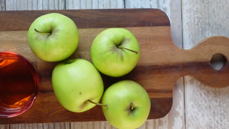 manzanas verdes y sidra de manzana en una tabla de corte de madera