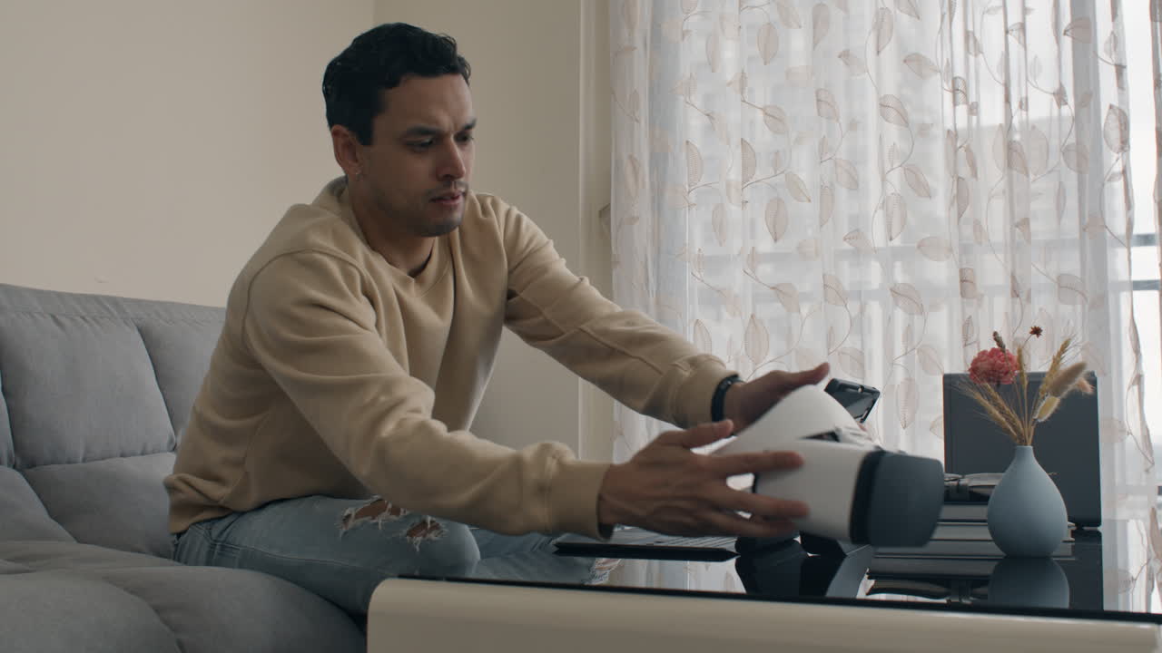 Frustrated man coding and testing VR headset. Engineer testing project on laptop and VR headset.