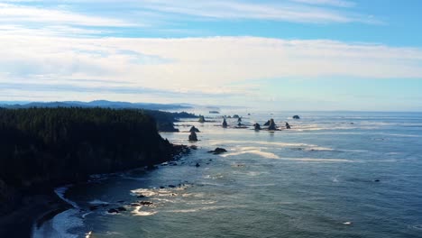 Impresionante-Dron-Aéreo-Que-Se-Inclina-Hacia-Arriba-De-La-Hermosa-Tercera-Playa-En-Forks,-Washington-Con-Grandes-Formaciones-Rocosas,-Rodeada-Por-Un-Bosque-De-Pinos-En-Los-Acantilados-Y-Arena-Dorada-En-Una-Cálida-Mañana-De-Verano