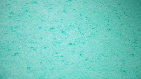 slow motion top-down shot of rain drops hitting pool surface, creating turbulent surface and ripples