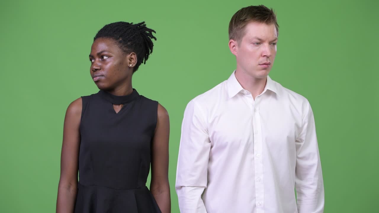 Two young multi-ethnic business couple looking in opposite directions together