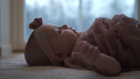 Infant-with-headband-and-dress-laying-on-back,-slow-motion