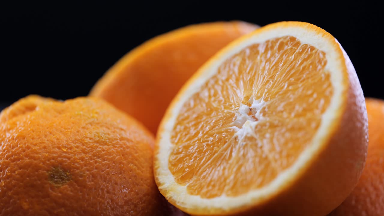 pila de naranjas recién cortadas frente al fondo negro, sartén de primer plano