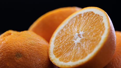 pila de naranjas recién cortadas frente al fondo negro, sartén de primer plano