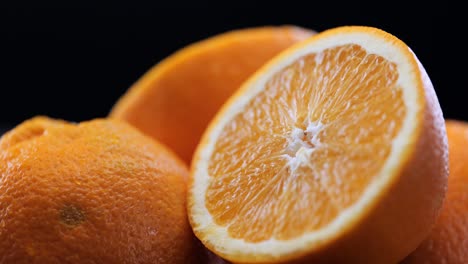 pile of freshly cut oranges in front of black background, close-up pan