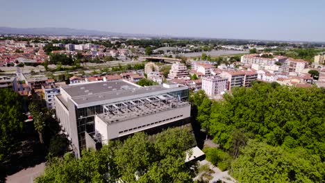 Majestätische-Bäume-Und-Moderne-Eleganz:-Eine-Atemberaubende-Luftdrehung-Des-Palais-Des-Congrès-In-Perpignan-In-Einer-Grünen-Oase