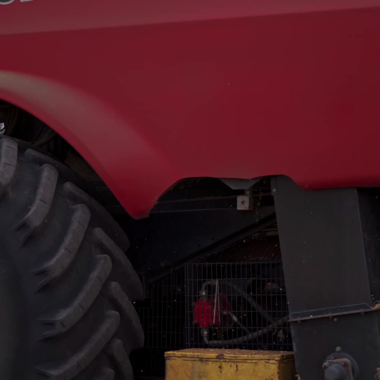 Huge mower mechanism cuts the wheat. Harvesting shears at work. Cloud of dust mixed with grains and straw coming out of massive wheels