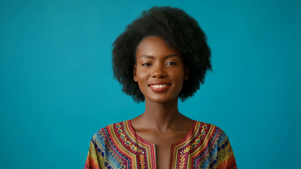 Ritratto di una bellissima donna nera sorridente con capelli afro che indossa un top etnico colorato su sfondo blu