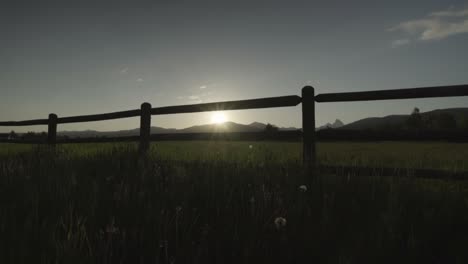 sunrise over the teton mountains through a farm fence in idaho