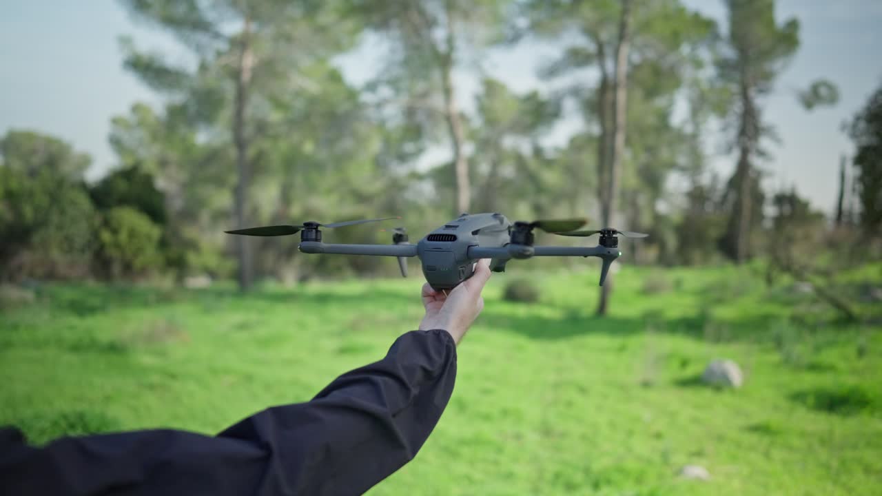Drone hovering low above a green forest clearing with trees in natural outdoor environment