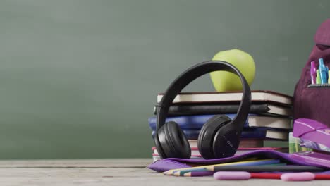 video de suministros escolares y libros en una mesa de madera sobre una pizarra