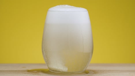 aspirin tablet dissolves in clear water in a glass on isolated yellow background