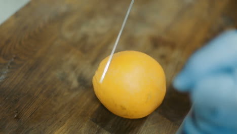 Chef Hands Cutting Orange. Chef hands cutting orange on table in kitchen