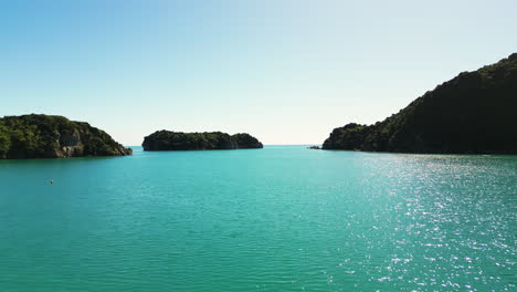 Small-remote-island-on-the-coast-of-New-Zealand,-aerial-forward-over-ocean