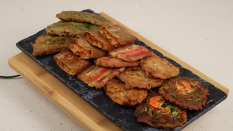 a crispy assortment of savory korean pancakes, with meat, seafood, and vegetables in every bite. 고기, 해산물, 채소가 어우러진 바삭한 모둠전 한 접시.