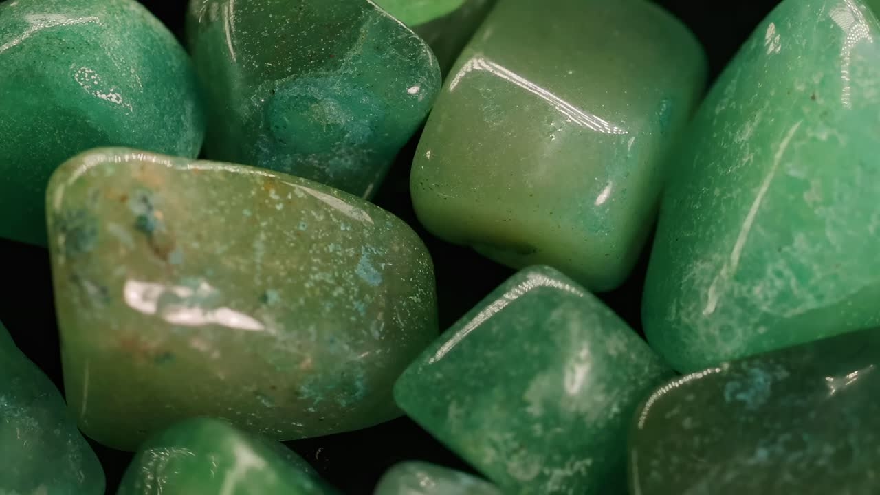 A detailed view of smooth, polished green stones with subtle reflections and textures.