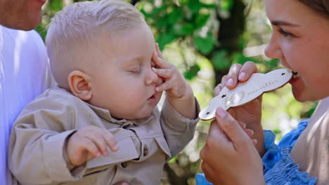 baby boy in dad's hands holding a wooden sign with ''ten months'' inscription. family portrait outdoors.