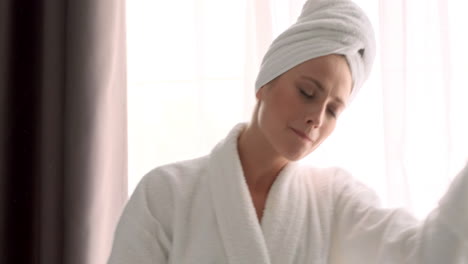 blonde woman in bathrobe dancing in hotel room.