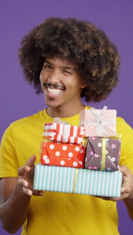 happy man with afro holding stack of gifts