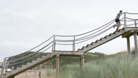 sportsman running on stairs at shore with mountains