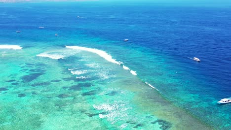 barcos que navegan por el mar azul junto a una laguna turquesa poco profunda con hermosos fondos marinos llenos de arrecifes de coral y rocas en antigua