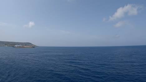 sailing on calm mediterranean sea with a clear sky ahead, mgaar port on the horizon