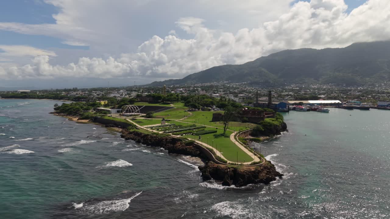 Ripresa aerea in allontanamento della Fortezza San Felipe a Puerto Plata, Repubblica Dominicana. Ampia vista della fortezza coloniale in pietra, del parco paesaggistico e della città costiera ai piedi della montagna.