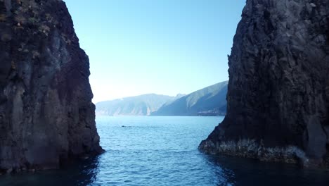 drone flying between two rocky sea stacks in portugal