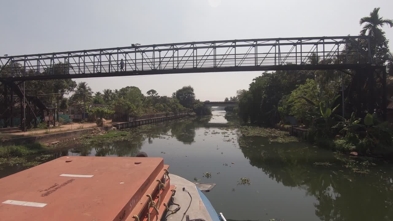 vista panorámica desde un barco que viaja por vía fluvial y bajo un puente peatonal en alappuzha, india