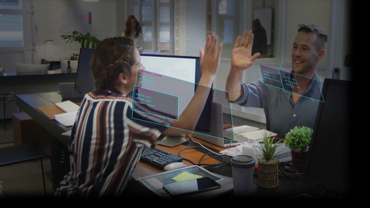 Due impiegati che usano la UI, si danno il cinque sopra il divisorio celebrando la ripresa della digitazione mentre un collega passa.