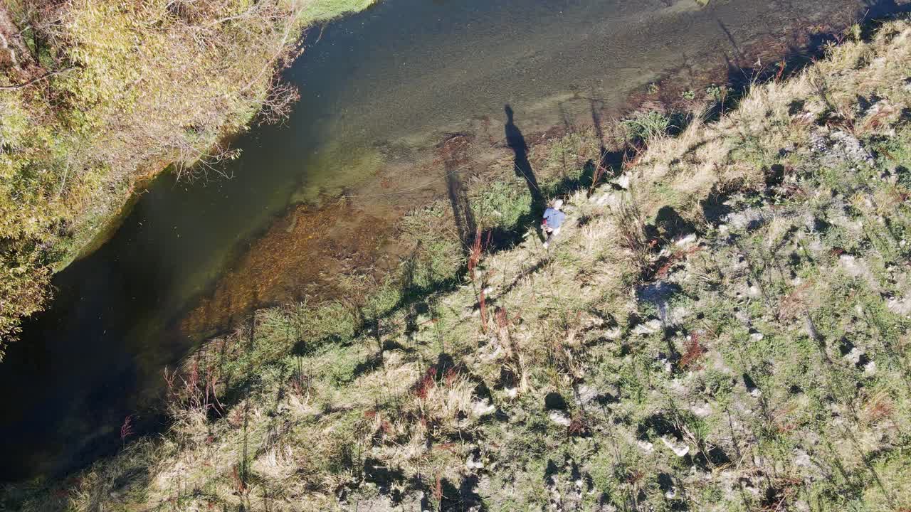 antena estática - pescador de mosca arrastrando la línea a lo largo del río mientras camina