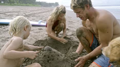 family with kid building sandcastle on beach