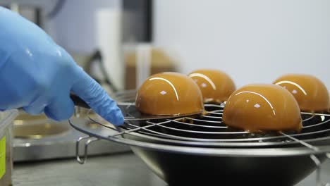 proceso de creación de deliciosos postres. manos de confiteros irreconocibles con guantes azules toman el pastel de la bandeja y lo decoran con patatas fritas.