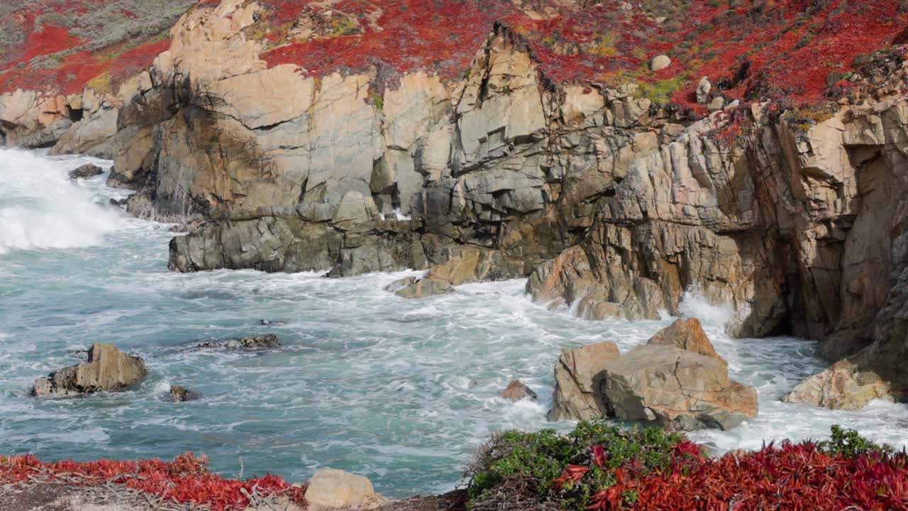 toma cercana de grandes olas rompiendo contra la costa irregular de big sur en garrapata, acantilados cubiertos de iceplant rojo en cámara lenta