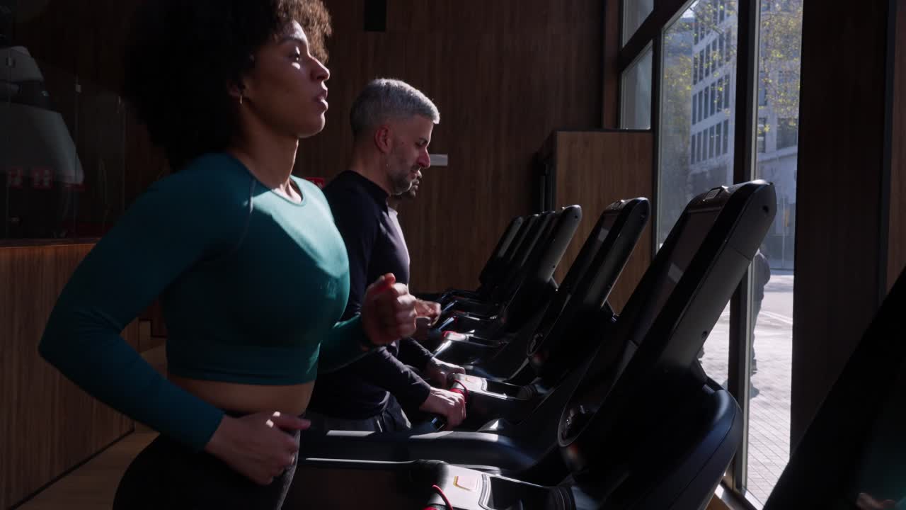 Donna e uomo che corrono sui tapis roulant in una palestra moderna