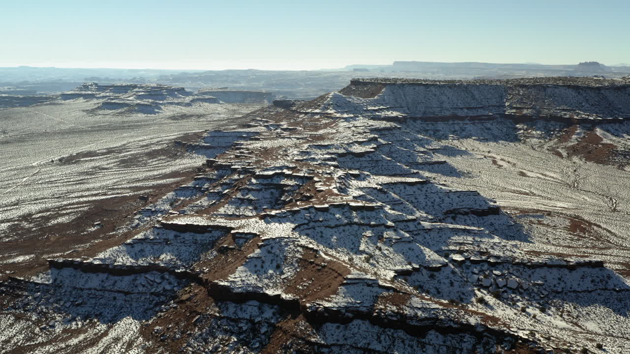 Snow-dusted mesas and canyons in a vast desert landscape