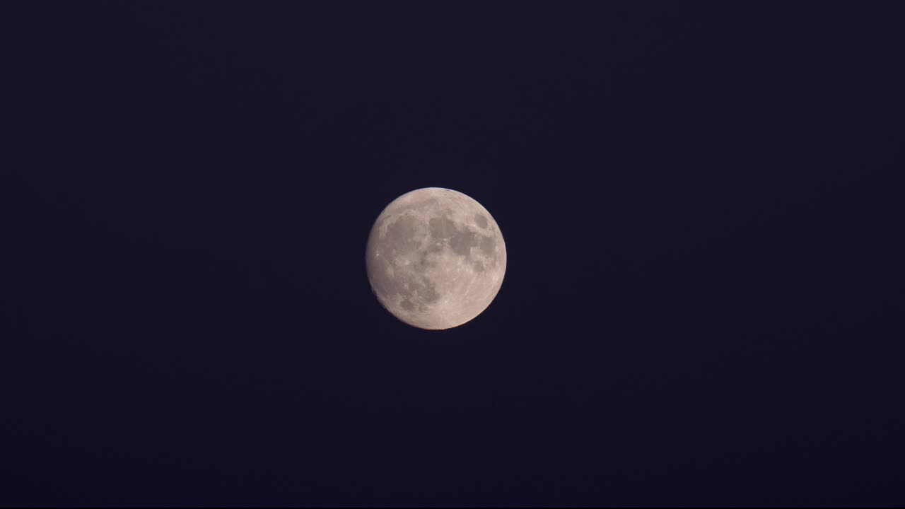 Plano detalhe de uma superlua da colheita sobre um céu escuro.
