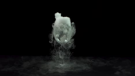 dry ice bubbling in wine glass at black background. slow motion