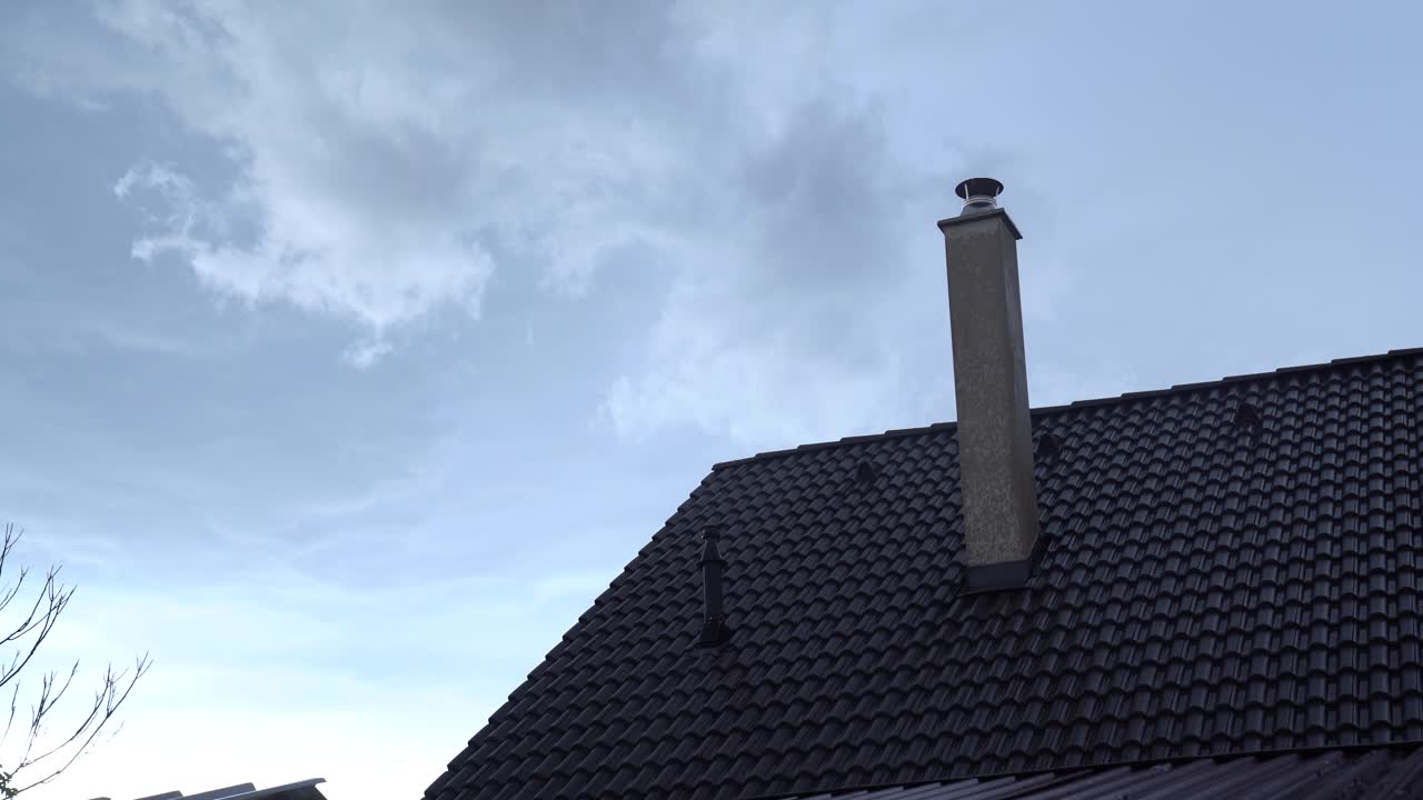 techo de la casa y chimenea bajo un cielo nublado en un día lluvioso, lluvia ligera cayendo