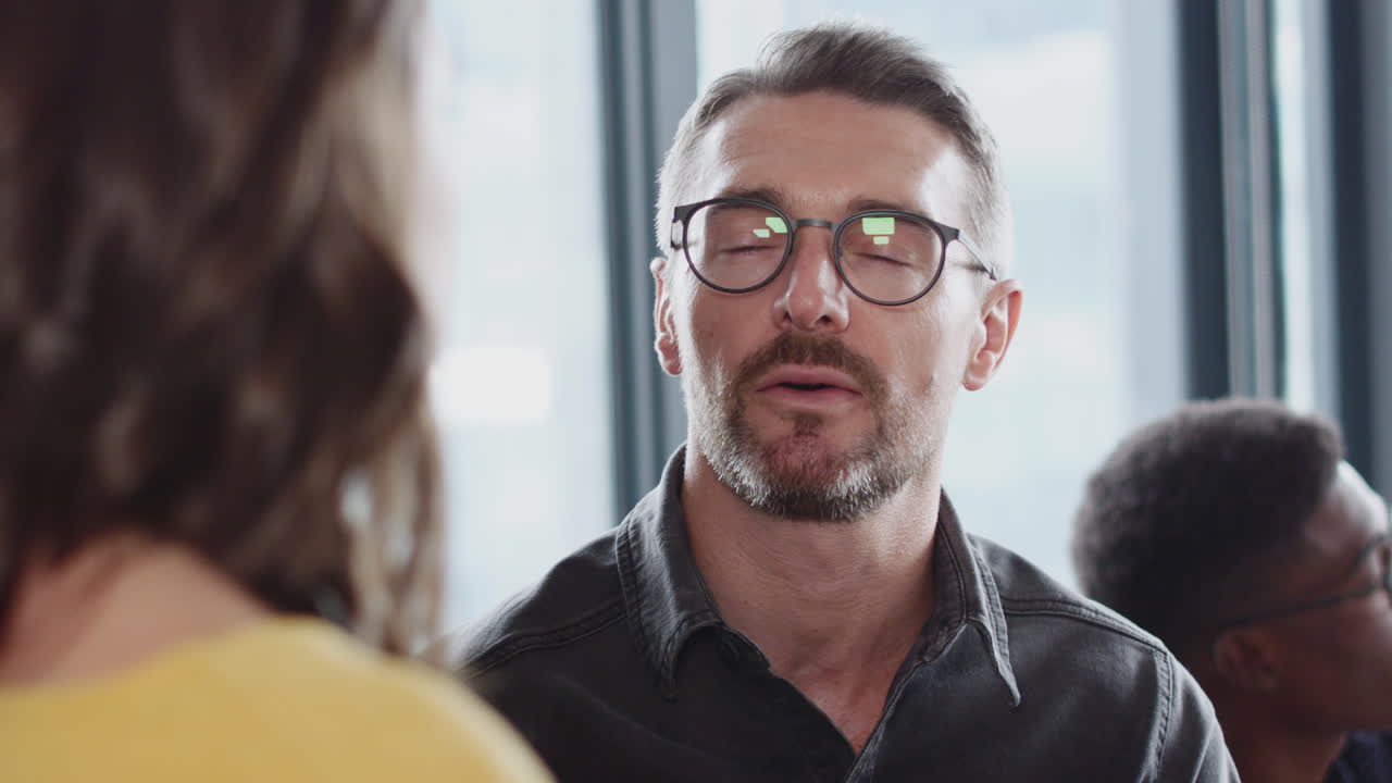 hombre blanco de mediana edad creativo hablando con un colega en una oficina ocupada, de cerca, enfoque selectivo