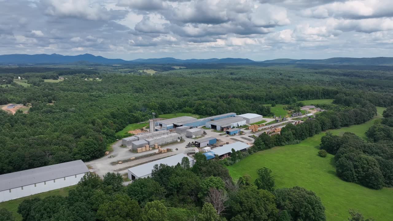 Industrial area, factory and warehouses surrounded by green forest trees in Virginia. Cloudy summer day in America. Aerial wide shot
