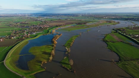 wide aerial orbiting view of the lek river near nieuwegein netherlands, where the rivers have swelled to about five times their normal size and overrun the banks flooding the farmland and towns