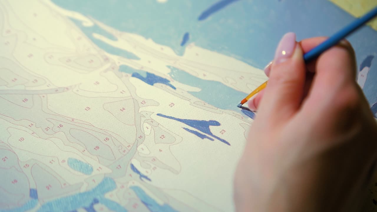 작은 페인트 브러시를 들고 캔버스 템플릿에 밝은 회색 아크릴 페인트로 그림을 그리는 클로즈업 여성 아티스트 손, 느린 동작 샷 닫기