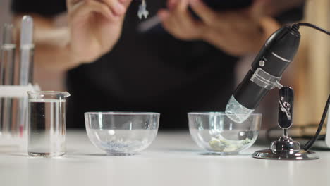 Scientist-puts-purple-crystals-into-small-glass-bowl-in-lab