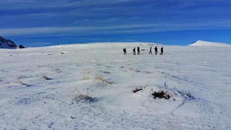 un grupo de personas haciendo senderismo en las tierras altas cubiertas de nieve en un soleado y frío día de invierno