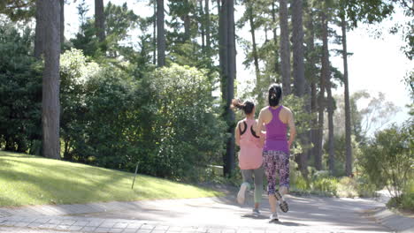 asian female friends running near forest on sunny day, slow motion