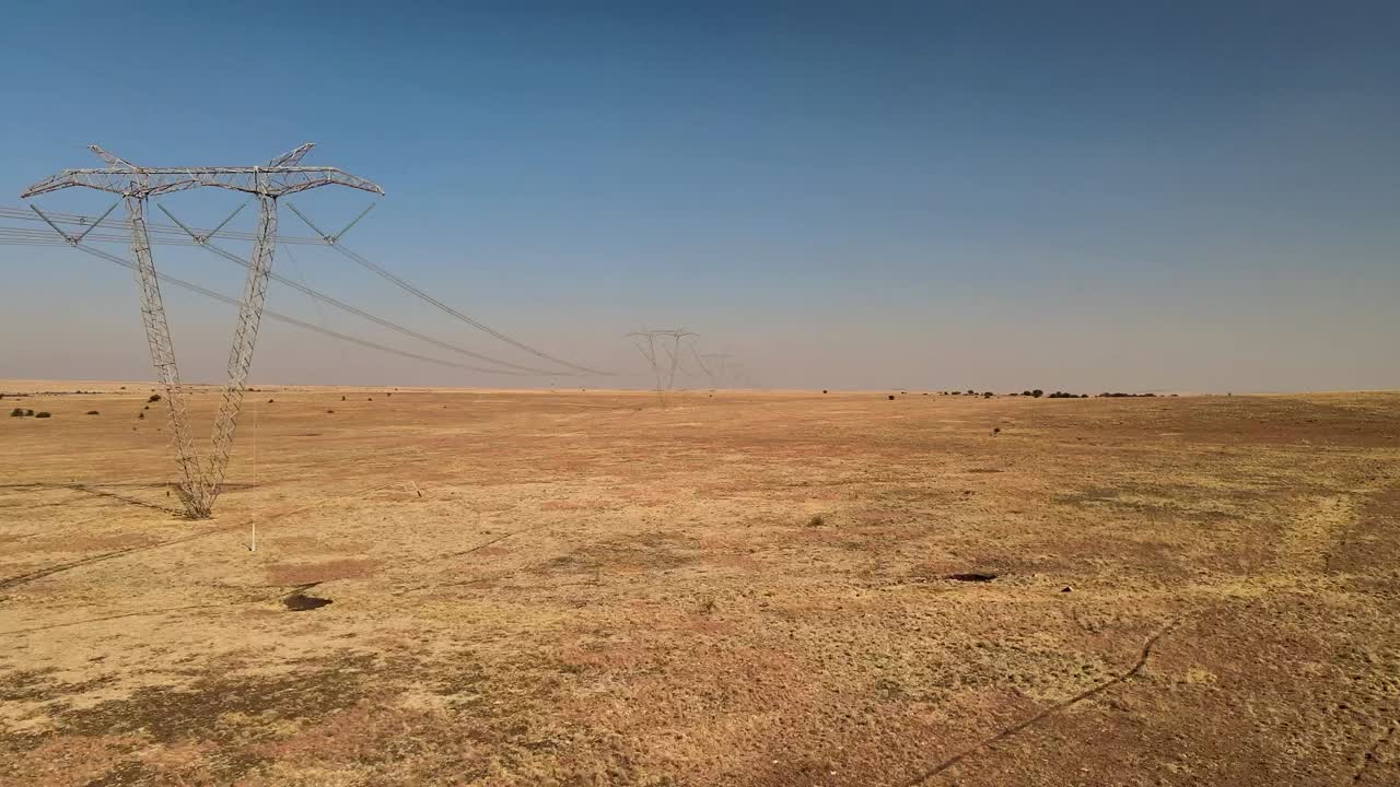líneas eléctricas expansivas de alto voltaje que se extienden a través de tierras de cultivo rurales en un paisaje rural remoto - capturado con un avión no tripulado