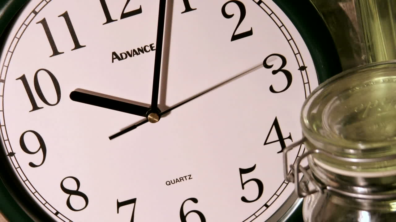 A second hand moves counterclockwise as minute and hour hands rapidly mark time on a clock face
