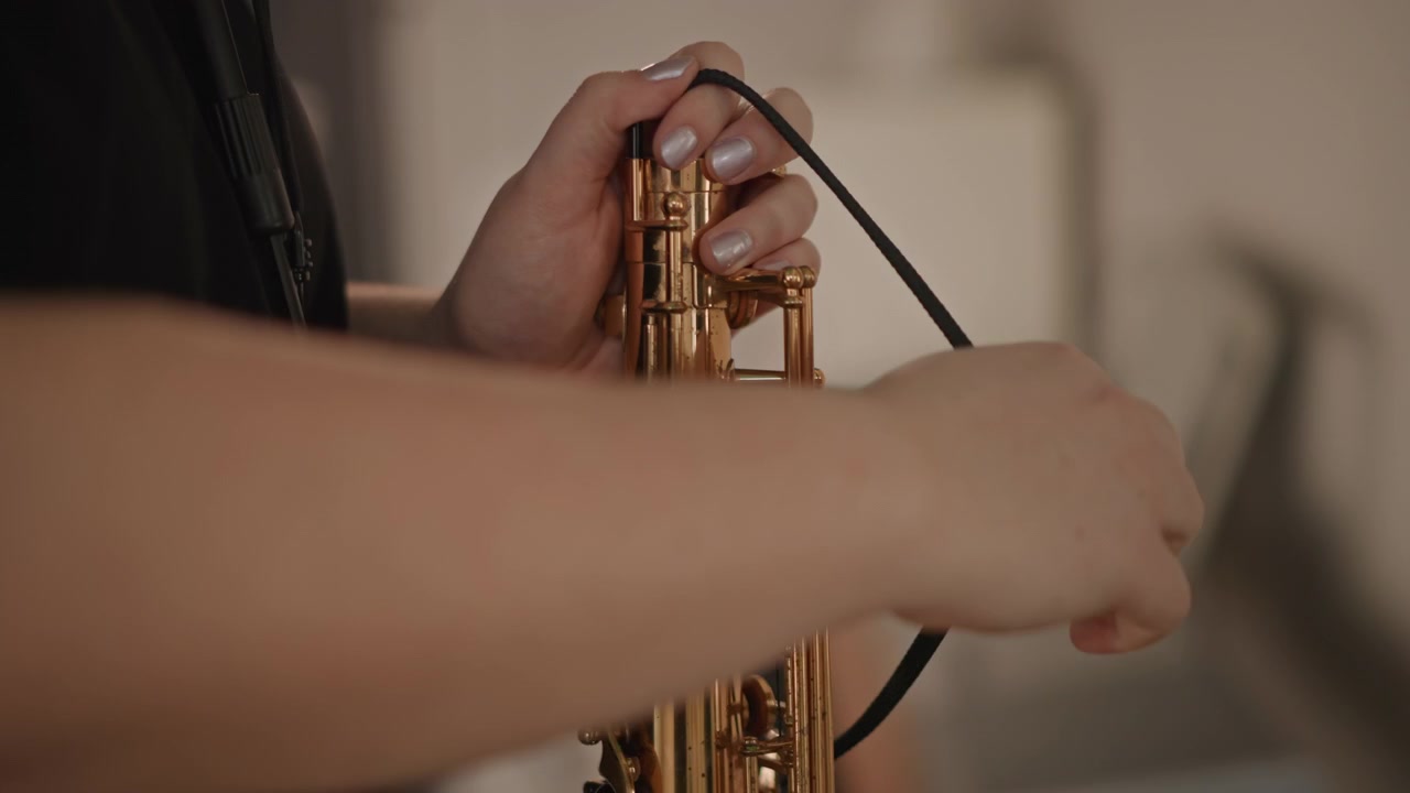 Procedimiento de limpieza cuidadosa de saxofón. Rutina de estudio para el mantenimiento de llaves y almohadillas de saxofón. Educador caucásico prepara cuidadosamente el saxofón limpiándolo y ajustándolo para la próxima lección