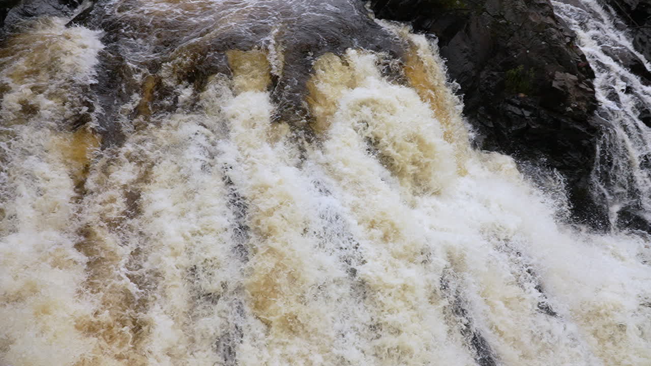 Slow motion view of water cascading down a waterfall into a scenic lake
